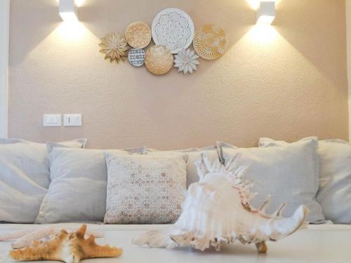 a white couch with pillows and a shell on it at Villa Luna - Vacanza a Villasimius vicino alle spiagge più rinomate della costa in Villasimius