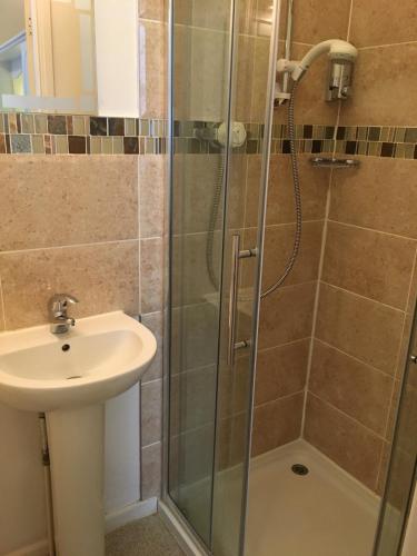 a shower with a glass door next to a sink at Bella Vista Hotel in Weston-super-Mare