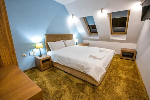 um quarto com uma cama com lençóis brancos e 2 janelas em Hotel Andon Angelov em Sandanski