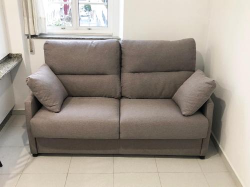 a brown couch in a room with a window at Pitelos Apartment in Santiago de Compostela