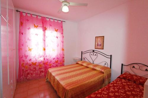 una camera con due letti e una finestra con tende rosa di Mirto House a Torre Pali