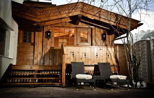 a wooden cabin with two chairs and a table at Sporthotel Neustift in Neustift im Stubaital