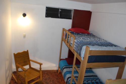 a small bedroom with a bunk bed and a chair at Kame House hostel in Huaraz