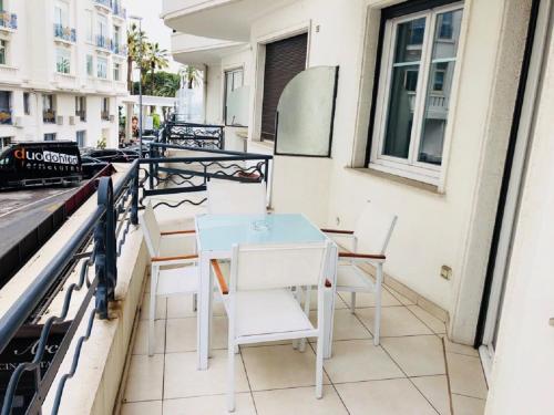 een tafel en stoelen op het balkon van een gebouw bij Ô Palais des Iles Two Bedroom Cannes in Cannes