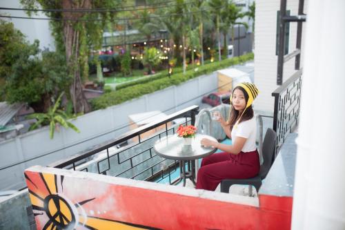 a woman sitting at a table on a balcony at Beehive Phuket Old Town Hostel in Phuket Town