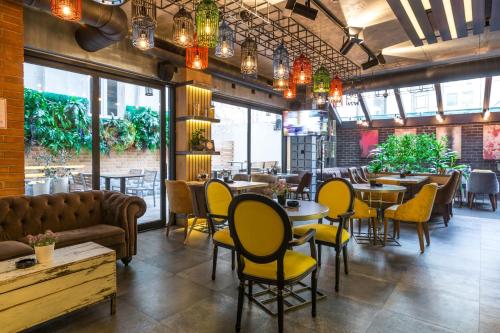 a restaurant with tables and chairs and a couch at Hotel Passpartù Home Garni in Belgrade