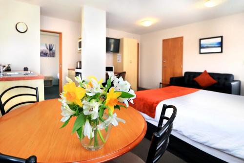 a room with a table with a vase of flowers on it at Bella Vista Motel Invercargill in Invercargill