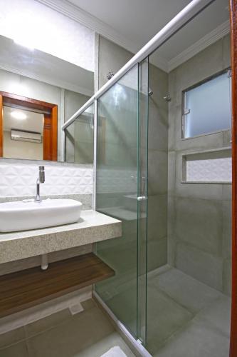 a bathroom with a sink and a glass shower at MDJ Pousada in Cabo Frio