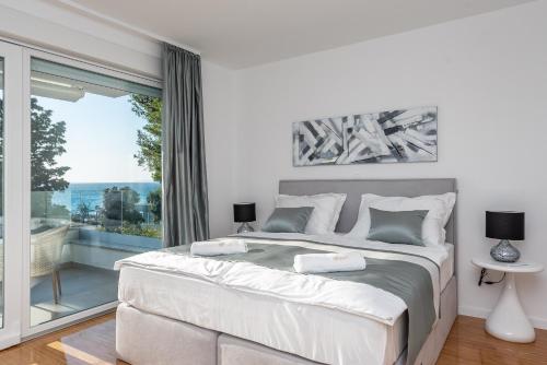 a bedroom with a large bed and a large window at Luxury apartment SUNSET with private pool and jacuzzi in Novalja