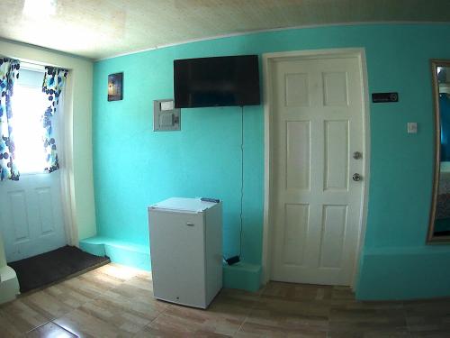 a room with a refrigerator and a television on the wall at Jem Gems in Christ Church