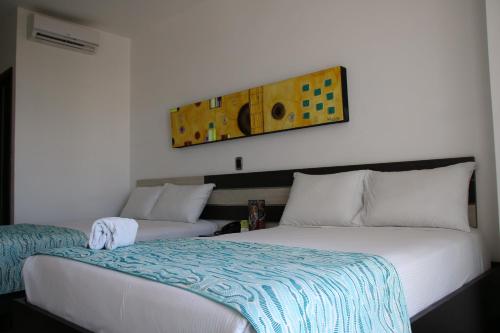 a bedroom with two beds and a painting on the wall at Hotel Guaitipan Plaza in Pitalito