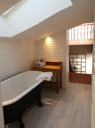 La salle de bains est pourvue d'une baignoire et d'une table. dans l'établissement LA VILLA DES CHAMPS, à Lille
