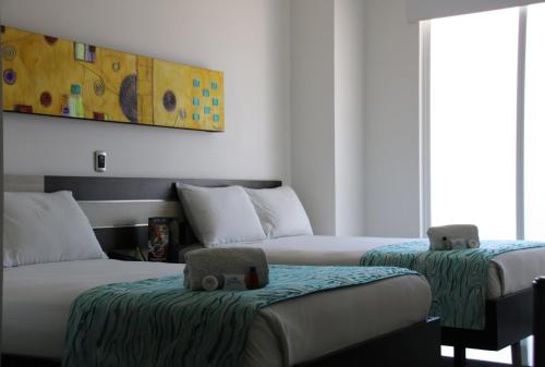 a room with two beds and a painting on the wall at Hotel Guaitipan Plaza in Pitalito