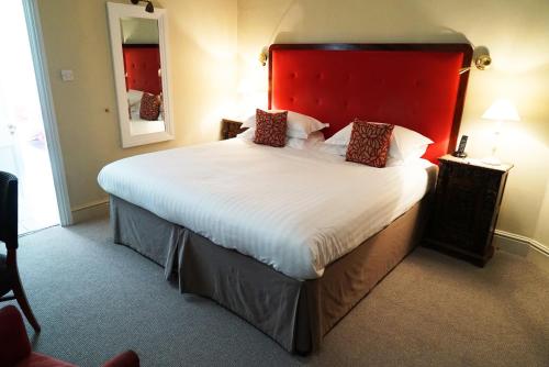 a bedroom with a large bed with a red headboard at Cotswold House Hotel and Spa - "A Bespoke Hotel" in Chipping Campden