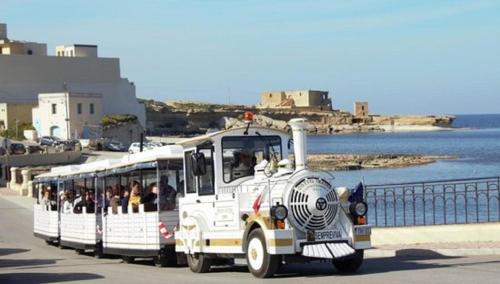 a white bus filled with people driving down a street at Diamonds Luxury Apartments in Marsalforn