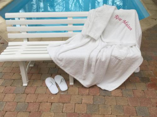 un banc blanc avec une couverture et une paire de chaussures dans l'établissement Rose Garden Mezzanine, à Giverny