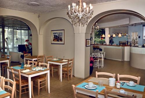 a restaurant with tables and chairs and a kitchen at Hotel Santiago in Milano Marittima