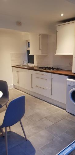 ロンドンにあるBeautiful home in Londonのキッチン(白いキャビネット、青い椅子付)