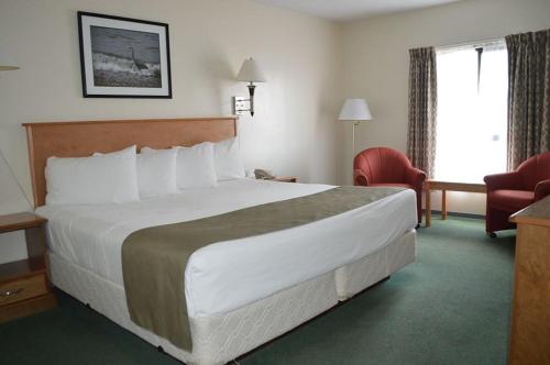 una habitación de hotel con una cama grande y una silla en Driftwood Inn, en Sechelt