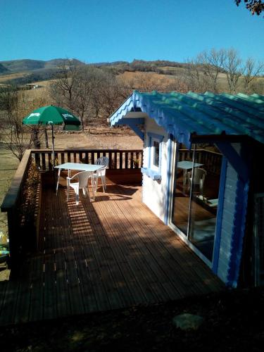 a wooden deck with a table and an umbrella at Camping du Moulin de Thoard in Thoard