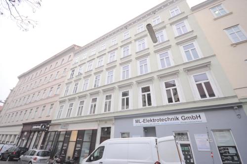 ein großes weißes Gebäude auf einer Straße mit Autos vor dem Haus in der Unterkunft Ferienwohnung Schloessel 26-26 in Wien