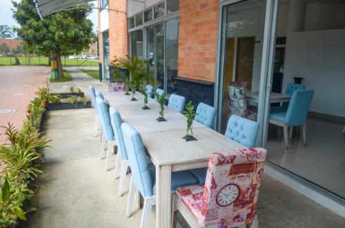 a long wooden table with blue chairs and a table with at Llanogrande Airport by Bernalo Hotels in Rionegro