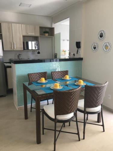 a dining room table with chairs and a kitchen at Flat Capitania Varam in Guarujá