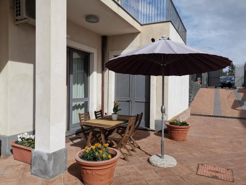 a patio with a wooden table and an umbrella at Floris Home tra Mare e Montagna in Zafferana Etnea