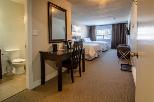 プリンスジョージにあるNorthwood Plaza Hotelのベッド、デスク、バスルームが備わるホテルルームです。
