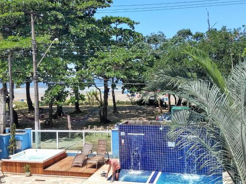 a man standing next to a swimming pool at Pousada Vistazul - Pé na Areia in Bertioga