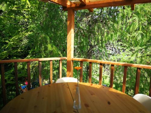 a wooden table on a deck with trees in the background at Sodyba Brazylija in Taraldžiai