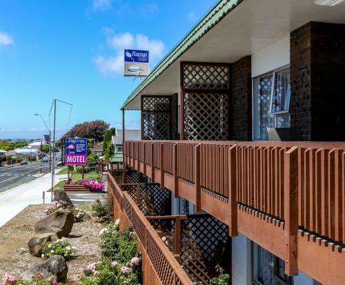 a building with a fence next to a street at Flamingo Motel in New Plymouth