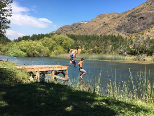 two boys jumping off a dock into a river at Ribera Cochrane, Cochrane in Cochrane