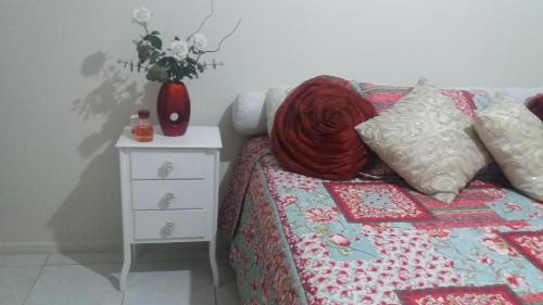 a bedroom with a bed and a night stand with a vase of flowers at Apartamento Vista Mar in São Vicente