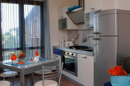 a kitchen with a refrigerator and a table with chairs at Residenza Principina in Principina Terra