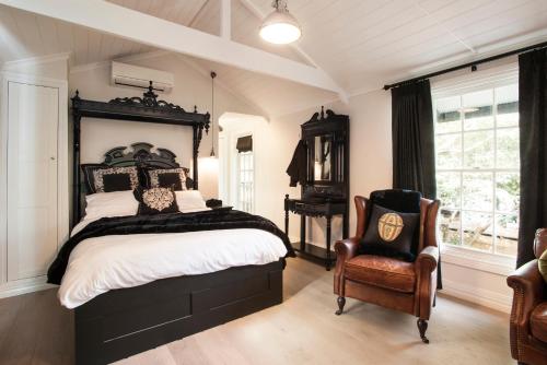 a bedroom with a large bed and a chair at Leddicott Cottage in Olinda