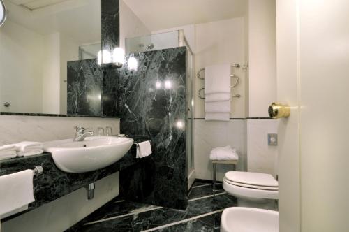 a bathroom with a sink and a toilet and a mirror at Grand Hotel Vesuvio in Naples