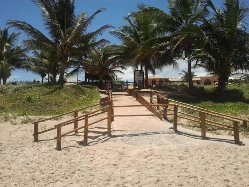 a wooden boardwalk on a beach with palm trees at SUMMER HOUSE GENIPABU in Guarajuba