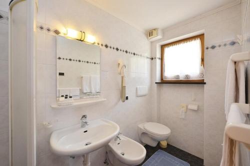 Baño blanco con lavabo y aseo en Hotel Malga Passerella, en Moena