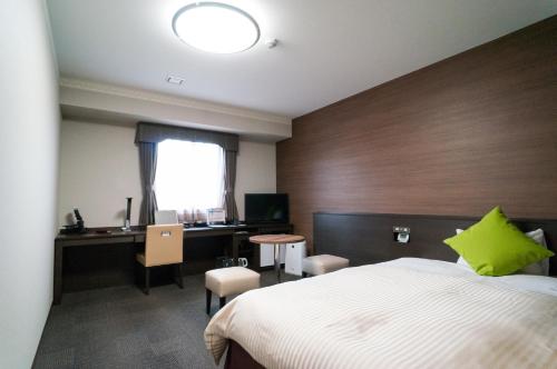 a bedroom with a bed and a desk with a green pillow at Hotel New Palace in Shingu