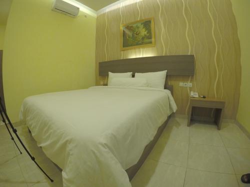 Muara Inn ternate في تيرنيت: غرفة نوم مع سرير أبيض كبير في غرفة