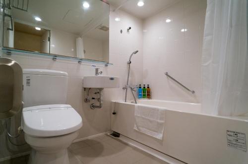 a white bathroom with a toilet and a bath tub at Hotel New Palace in Shingu