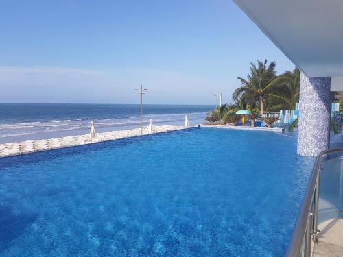una gran piscina azul junto a la playa en Departamento frente al mar Grand Diamond, en Tonsupa