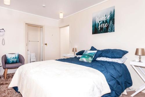 a bedroom with a large bed and a chair at Riverside Accommodation in Karangahake