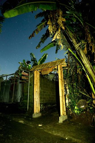 a small building with a wooden door next to a tree at Pondok Salacca#bamboohouse# in Candidasa