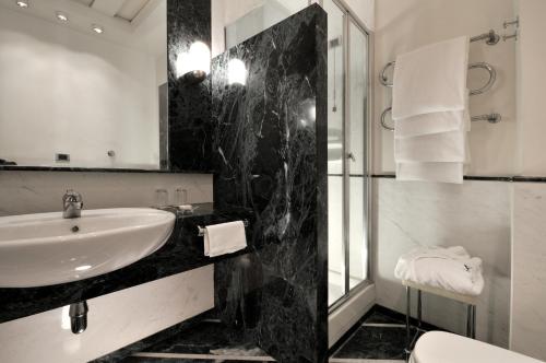 un bagno bianco e nero con lavandino e doccia di Grand Hotel Vesuvio a Napoli