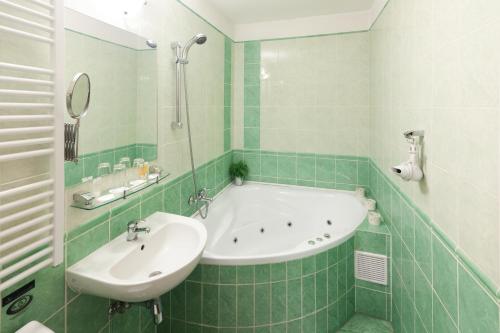 a green tiled bathroom with a tub and a sink at Pytloun Self Check-in Hotel Liberec in Liberec