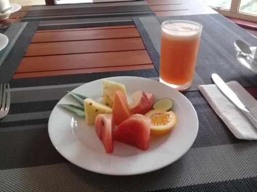 um prato de fruta e um copo de sumo de laranja em Water Front Home Stay em Anuradhapura