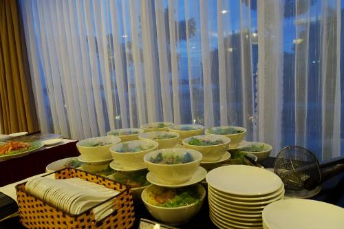 una mesa con tazones y platos blancos en una mesa en Khách sạn Sài Gòn Vĩnh Long, en Vĩnh Long
