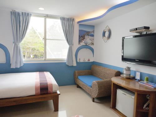 a bedroom with a bed and a tv and a chair at Kenting Sin Sin Hotel in Kenting